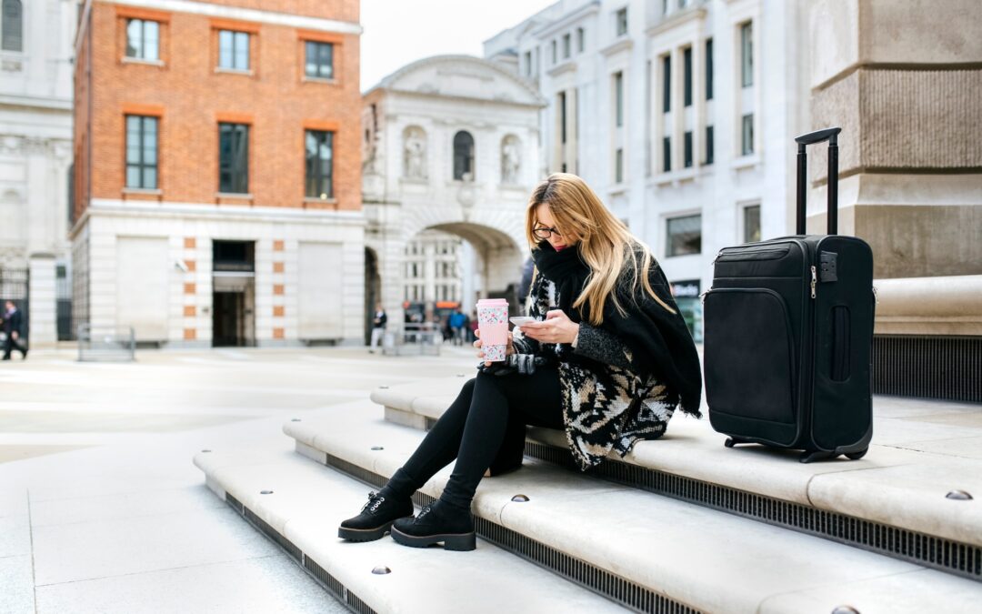 UK, London, young woman with luggage checking her cell phone on stairs